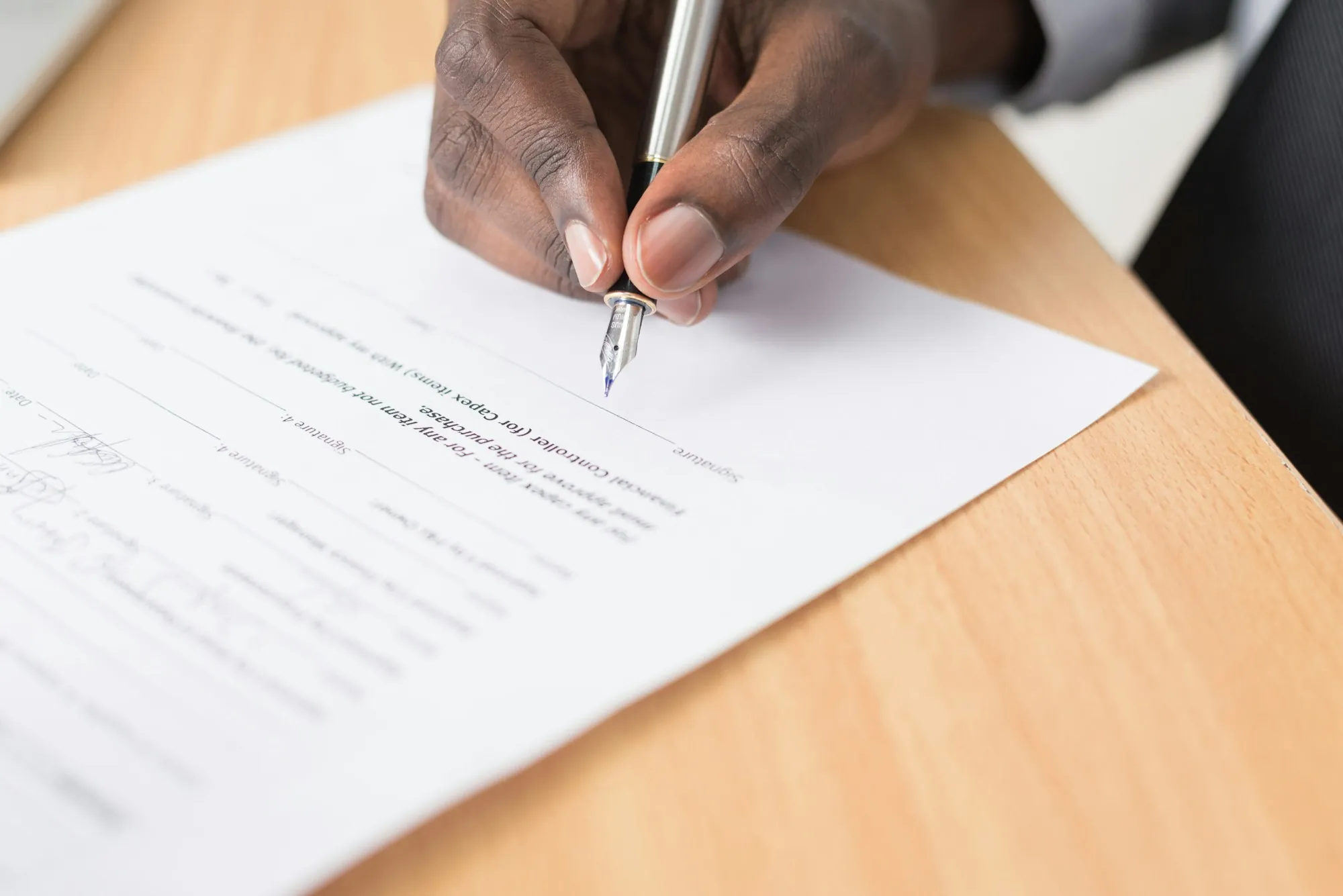 Hand writing on a sheet of paper on a wooden desk