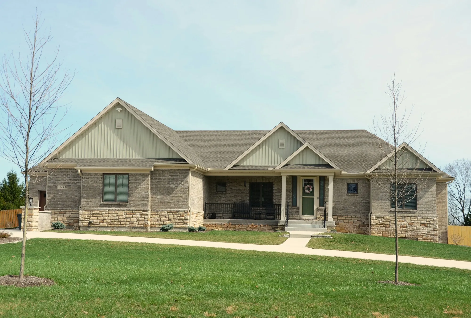 Ranch home with stone and siding and a broad lawn