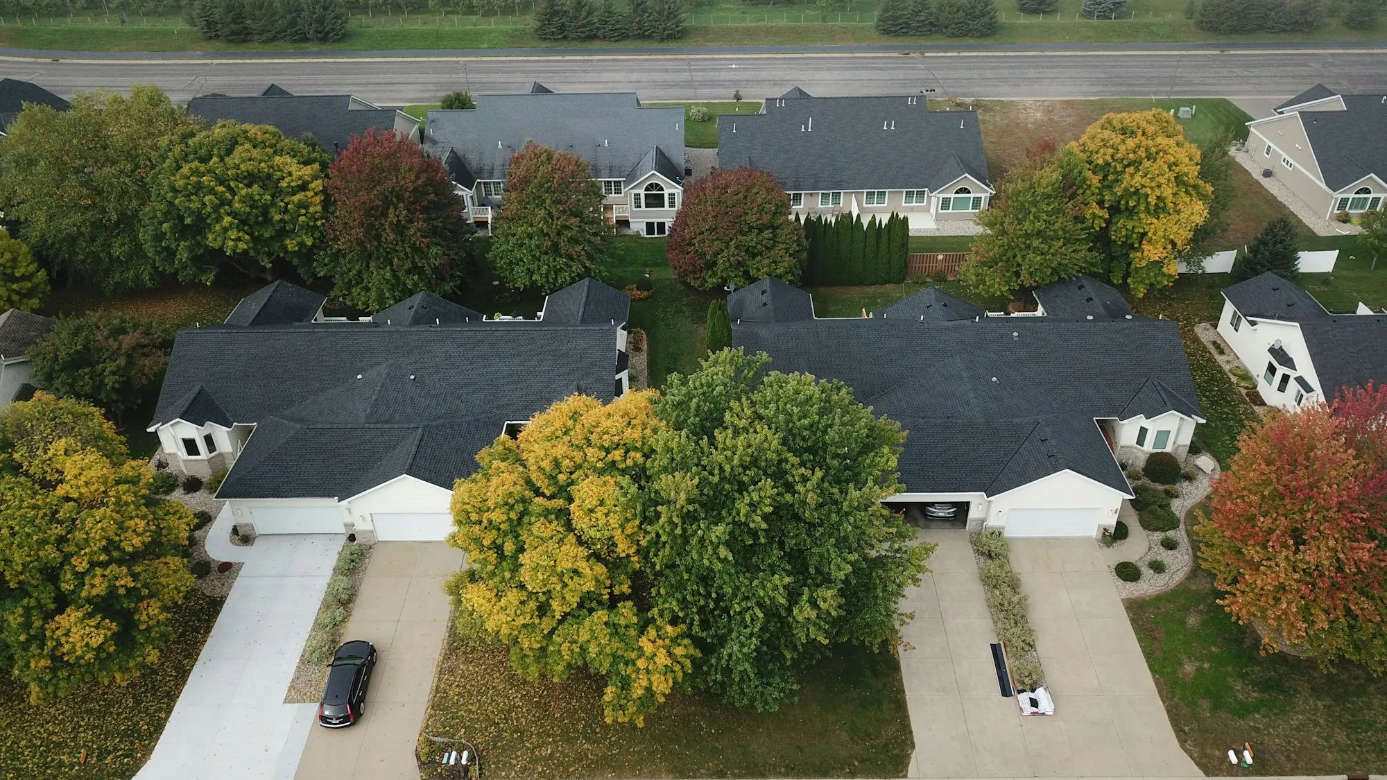 Aerial view of two suburban homes with driveways among autumn trees, the kind of roofs where leased solar panel removal comes up before a Richton Park reroof